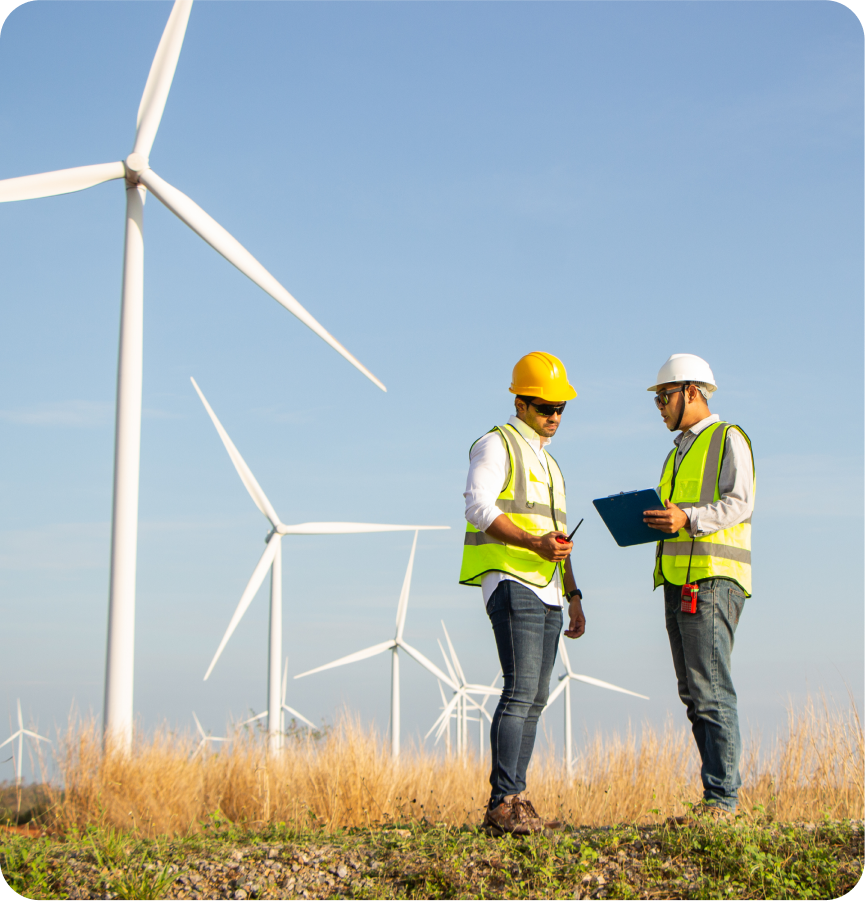 Two men in hard hats standing in front of a wind turbine